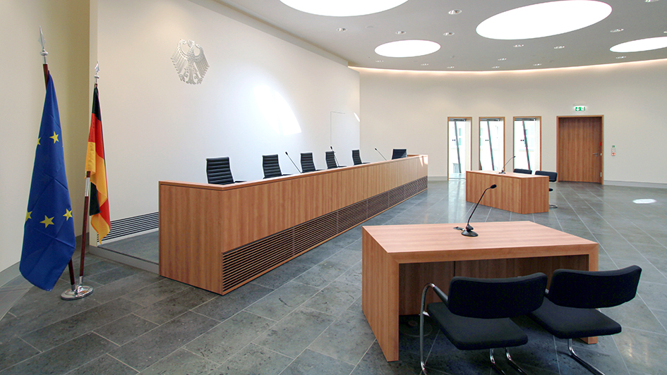 Blick auf die Richterbank im Elisabeth-Selbert-Saal mit Europafahne und Deutschlandfahne im Vordergrund