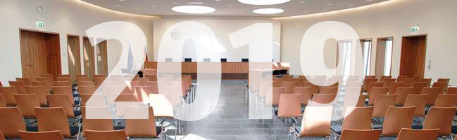 Blick auf die Richterbank im Elisabeth-Selbert-Saal des Bundessozialgerichts, davor ist die Jahreszahl 2019 eingeblendet.