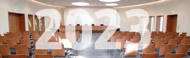 Blick auf die Richterbank im Elisabeth-Selbert-Saal des Bundessozialgerichts, davor ist die Jahreszahl 2023 eingeblendet.