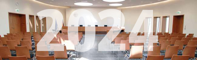 Blick auf die Richterbank im Elisabeth-Selbert-Saal des Bundessozialgerichts, davor ist die Jahreszahl 2024 eingeblendet.